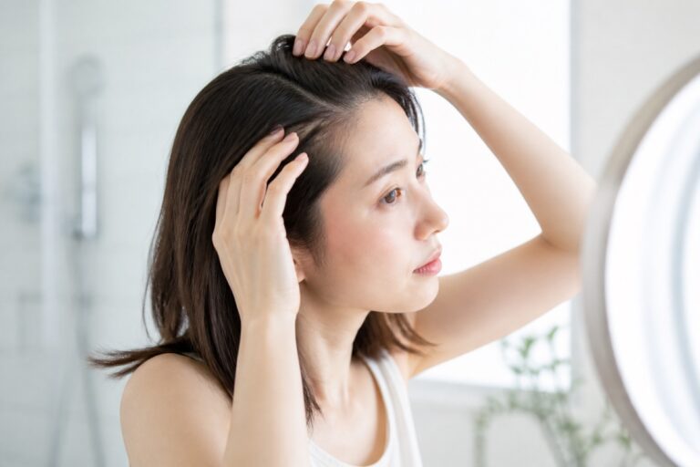 夏の頭皮のベタつきが気になり髪をかき分ける女性